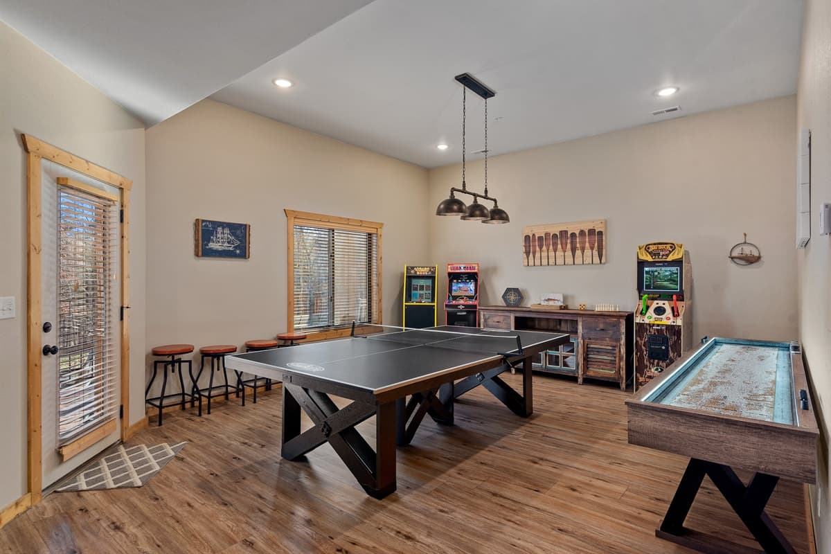 Lower level entertainment space with 3 arcade machines, ping pong, and shuffleboard